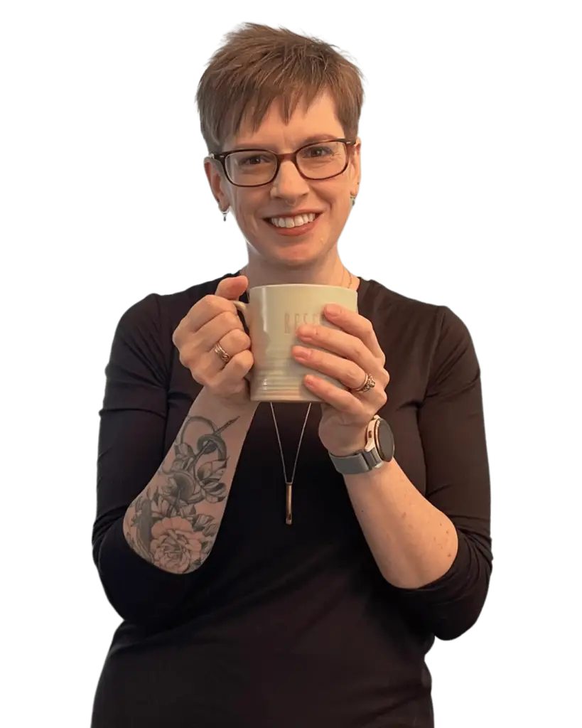 A picture of stress management for high achievers expert Avery, a white woman with a pixie cut and light brown hair holding a tea mug